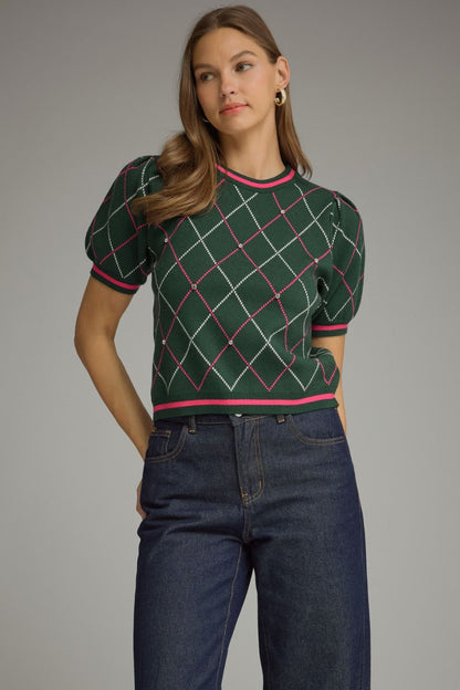 Green argyle short puff sleeve sweater top with pink and ivory lines and striped trim, styled with dark-wash jeans.